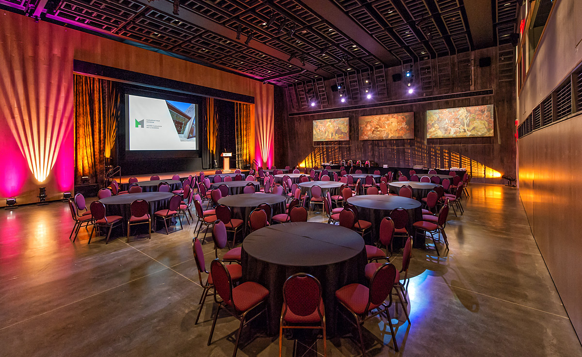 Une grande salle avec des tables, des chaises et un écran de projection au Musée canadien de la guerre d'Ottawa.