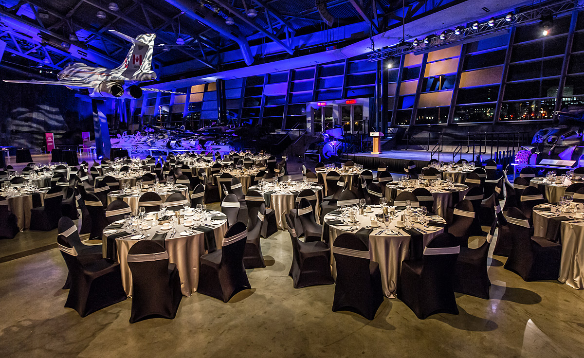 Une grande salle avec tables et chaises aménagées pour un dîner au Musée canadien de la guerre à Ottawa.