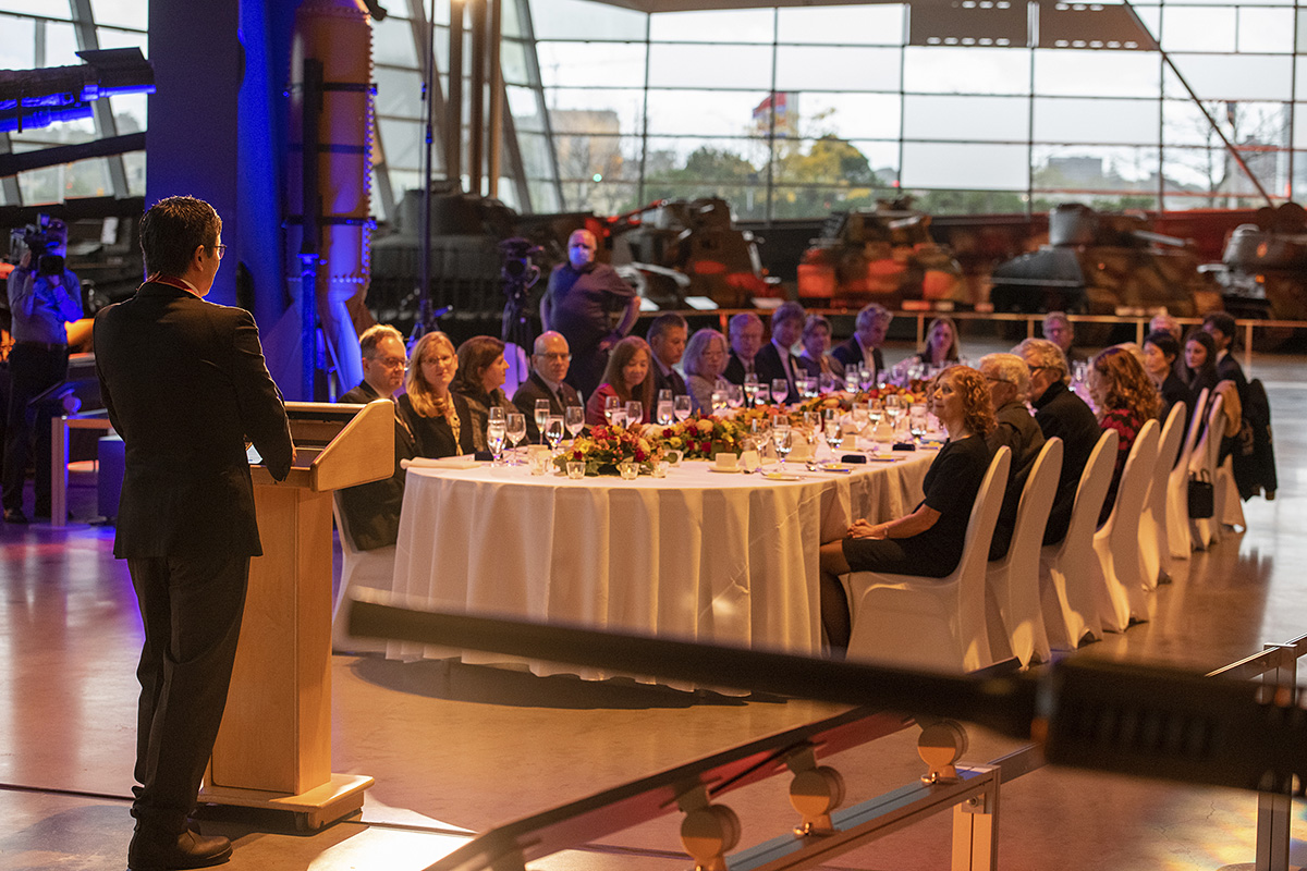 Un homme debout à une table devant une foule de gens au Musée canadien de la guerre à Ottawa.