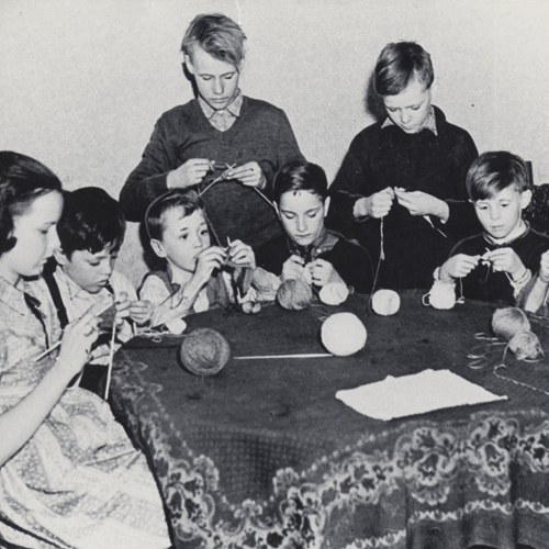 Un groupe d'enfants assis autour d'une table en train de tricoter au Musée canadien de la guerre à Ottawa.