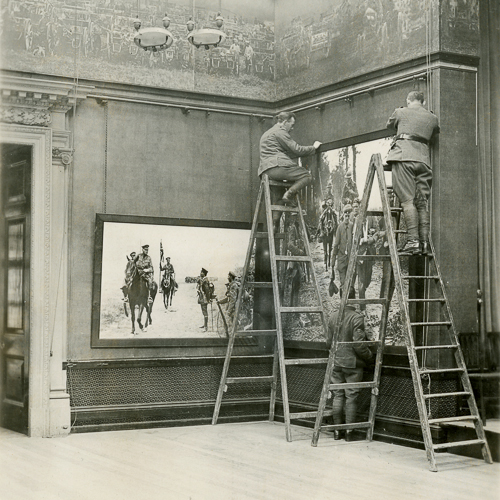 Deux hommes sur des échelles travaillant sur un tableau au Musée canadien de la guerre à Ottawa.