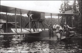 Un groupe de personnes debout à côté d’un biplan dans l’eau au Musée canadien de la guerre.