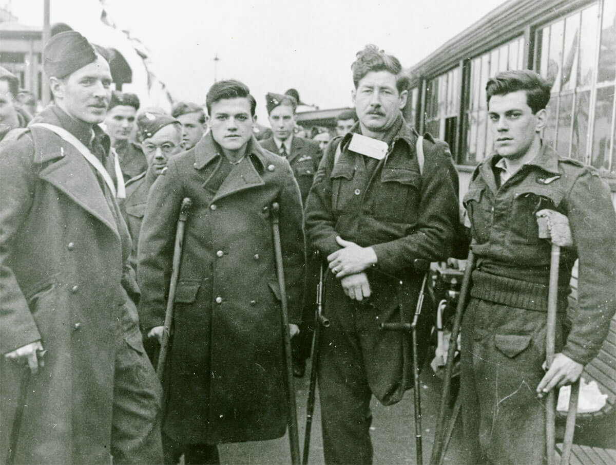 Un groupe d'hommes avec des béquilles debout à côté d'un train au Musée canadien de la guerre, à Ottawa.