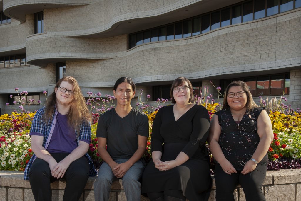 Quatre femmes assises sur un banc devant le Musée canadien de la guerre à Ottawa.