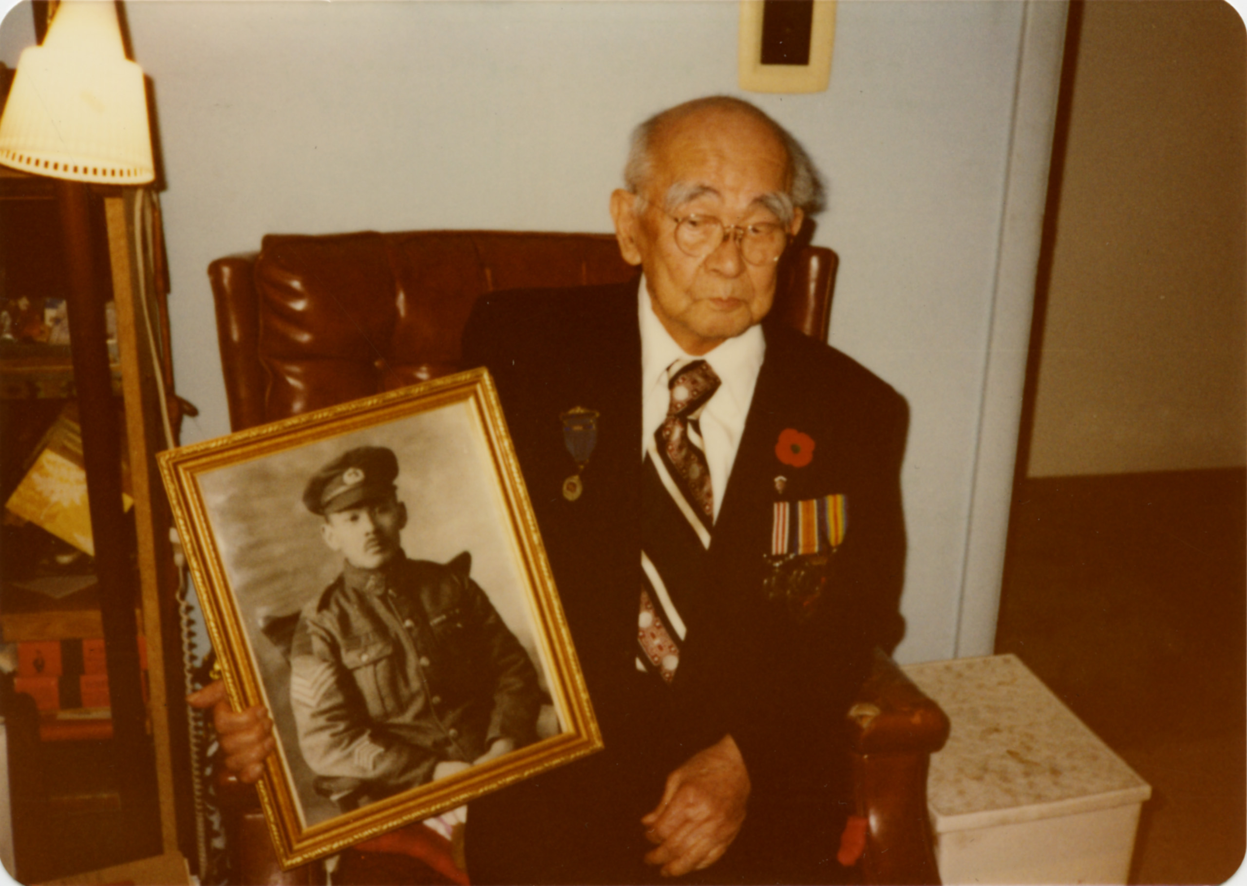 An older man holding a picture of a military man at the Canadian War Museum in Ottawa.