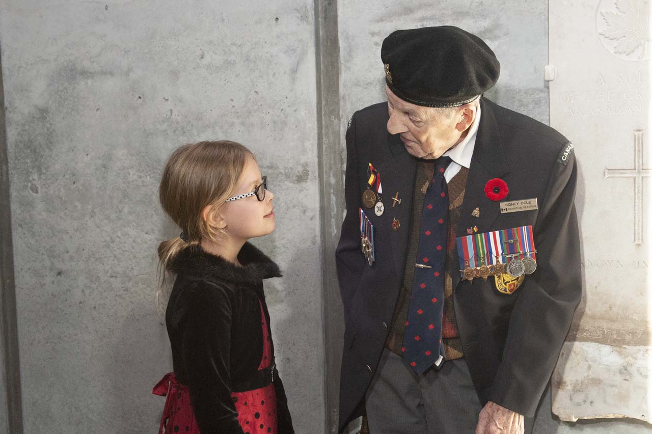 Une jeune fille parle à un vieil homme en costume.