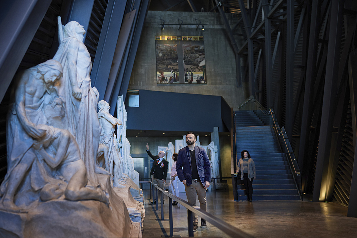 Un groupe de personnes traversant un musée avec des statues.