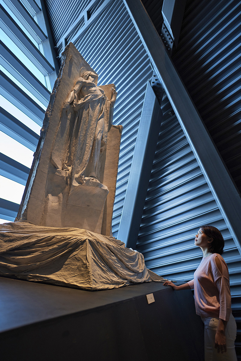 Une femme regardant une sculpture dans un musée.