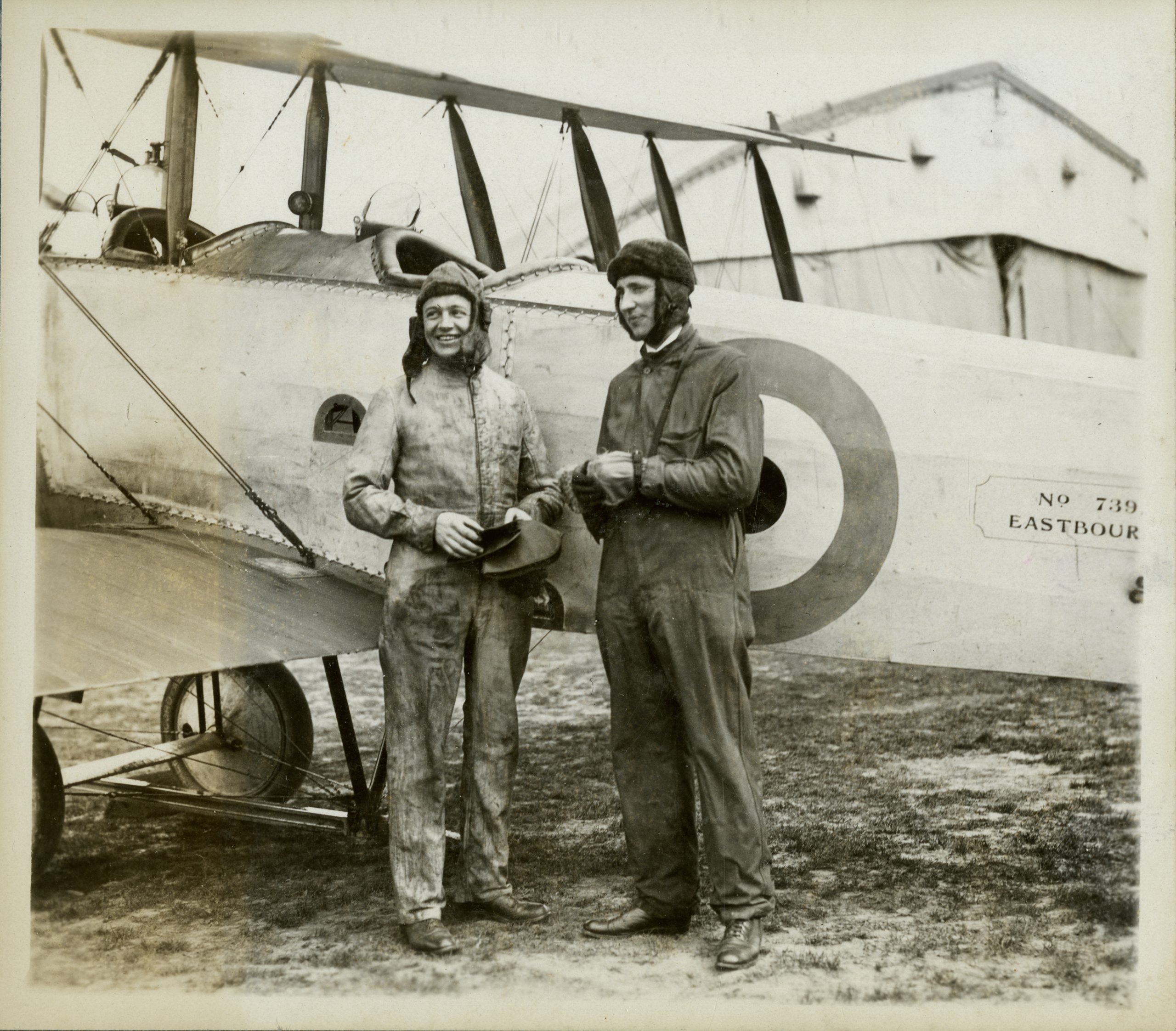 Two pilets standing in front of a WWI plane